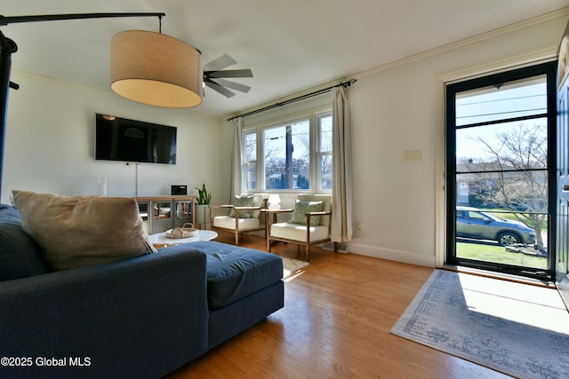 living room with ornamental molding, lofted ceiling, wood finished floors, baseboards, and ceiling fan