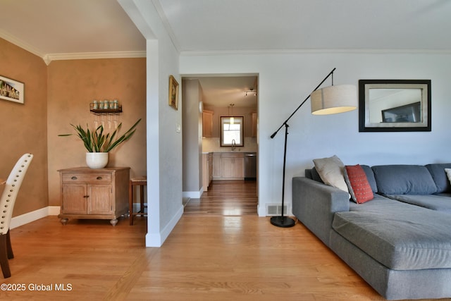 living room featuring light wood-style floors, baseboards, crown molding, and visible vents