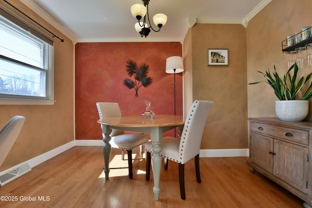 dining space with visible vents, light wood finished floors, crown molding, and baseboards