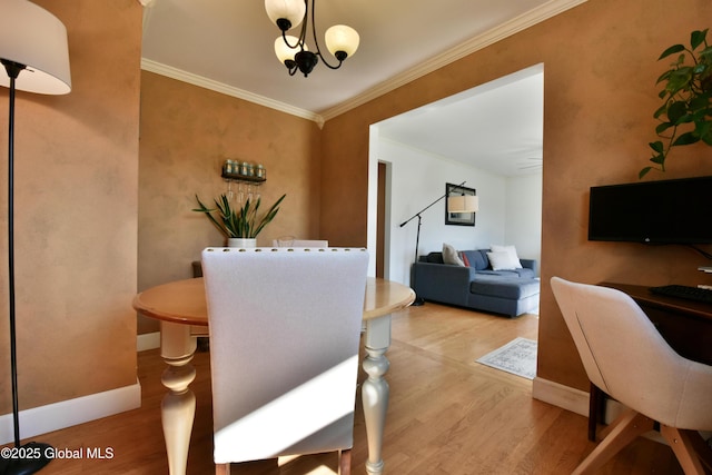 dining area featuring baseboards, ornamental molding, wood finished floors, and an inviting chandelier