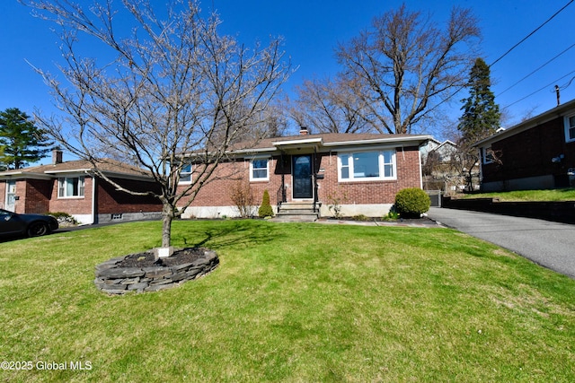 view of front of home featuring brick siding, a chimney, and a front yard