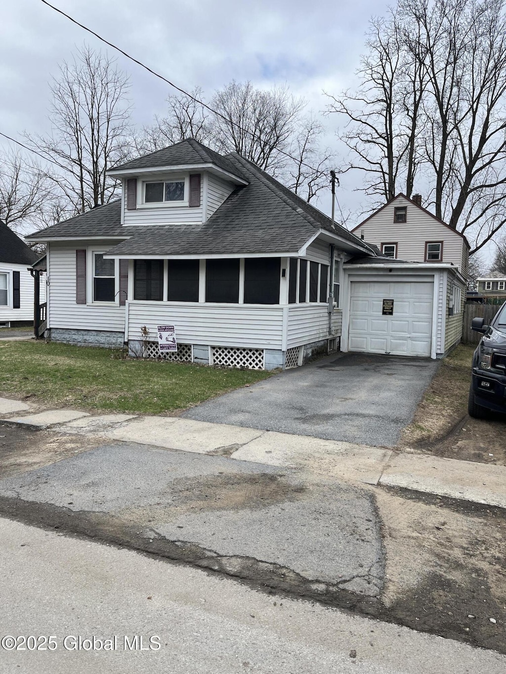 10 Liberty Pl, Hudson Falls, NY 12839 - bungalow-style home featuring roof with shingles, an outdoor structure, an attached garage, aphalt driveway, and a front yard