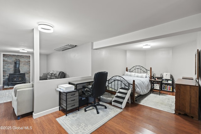 419 Brownell Rd, Malta, NY 12020 - bedroom featuring wood finished floors, a wood stove, baseboards, and visible vents