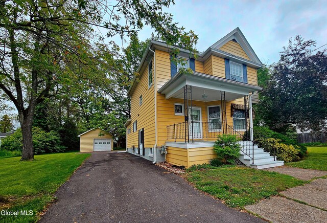 16 Oakwood Blvd, Hudson, NY 12534 - view of front facade featuring covered porch, an outdoor structure, asphalt driveway, a detached garage, and a front yard