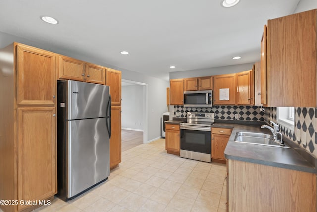 kitchen featuring decorative backsplash, dark countertops, recessed lighting, a sink, and stainless steel appliances