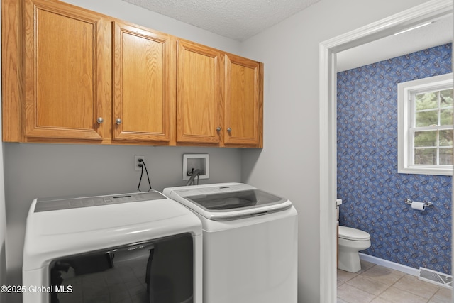 washroom with visible vents, baseboards, wallpapered walls, cabinet space, and independent washer and dryer