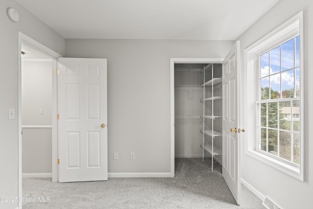 unfurnished bedroom featuring a closet, baseboards, multiple windows, and carpet flooring