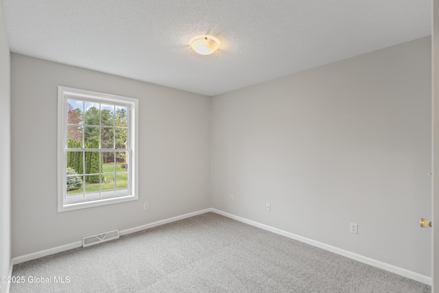 carpeted empty room featuring baseboards, a textured ceiling, and visible vents