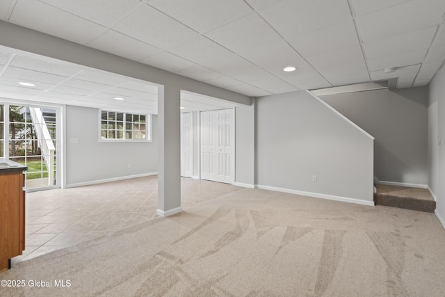 below grade area with carpet floors, baseboards, recessed lighting, and a paneled ceiling