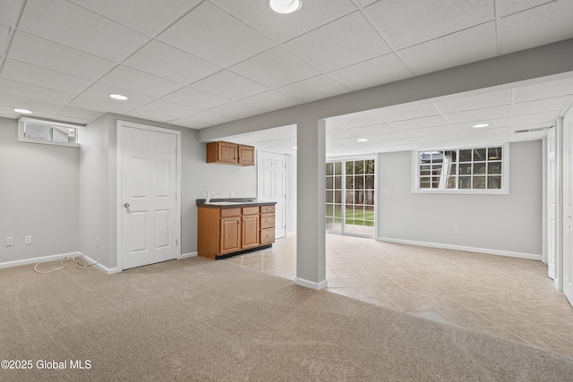 basement with baseboards, light carpet, and a paneled ceiling