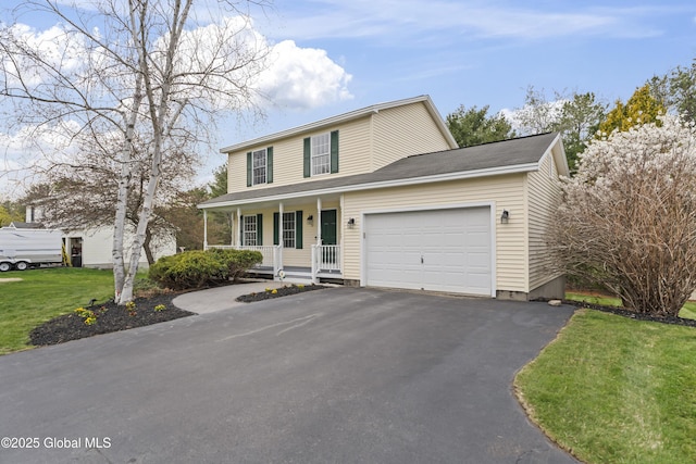 traditional-style house with a porch, an attached garage, driveway, and a front yard