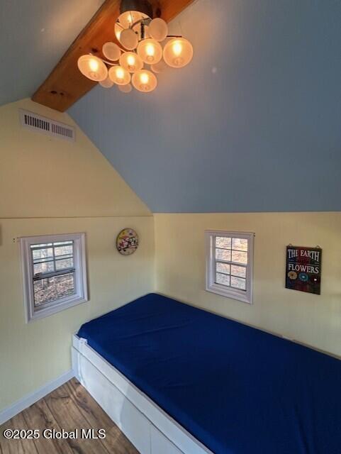 bedroom featuring visible vents, wood finished floors, baseboards, lofted ceiling with beams, and an inviting chandelier