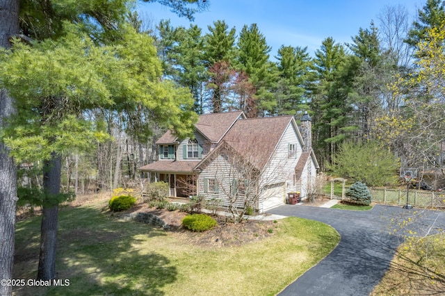 view of front of home featuring aphalt driveway, fence, a front yard, a chimney, and an attached garage