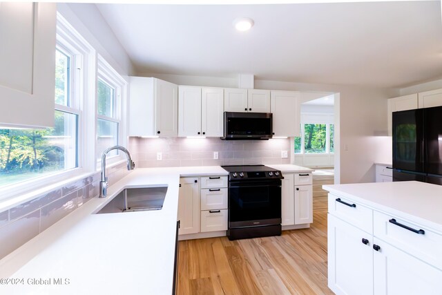 kitchen with a sink, black appliances, white cabinetry, and decorative backsplash