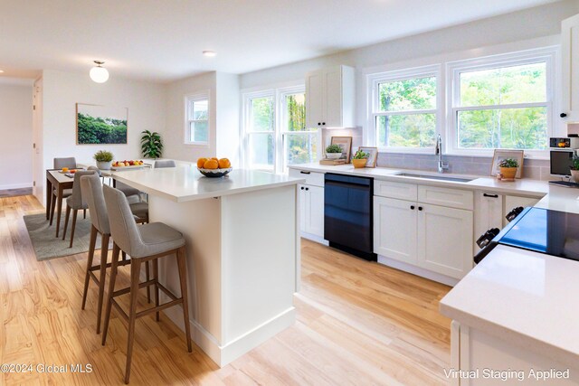 kitchen featuring a sink, light wood-style floors, a kitchen bar, and dishwasher