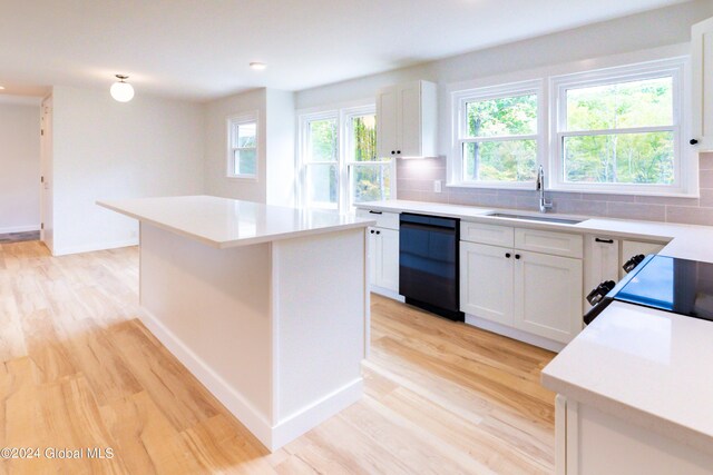 kitchen with tasteful backsplash, light wood-type flooring, a sink, and black dishwasher