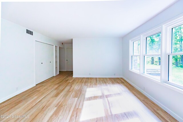 spare room with a healthy amount of sunlight, light wood finished floors, baseboards, and visible vents