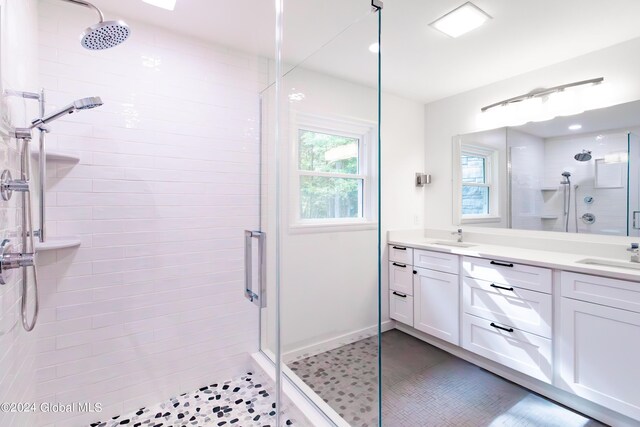 full bath featuring a shower stall, tile patterned floors, double vanity, and a sink