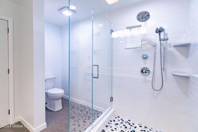 full bath with toilet, a stall shower, baseboards, and tile patterned floors