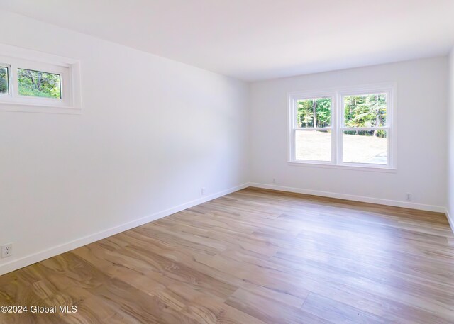 spare room with light wood-style floors, baseboards, and plenty of natural light