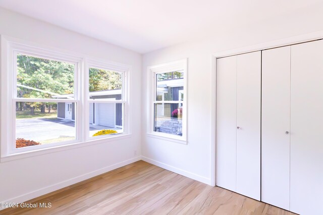 unfurnished bedroom with light wood-style flooring, a closet, and baseboards