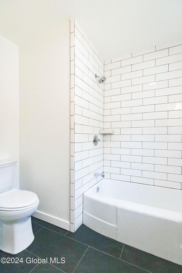 bathroom with toilet, tile patterned floors, baseboards, and shower / bathtub combination
