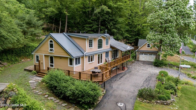 1141 N Shore Rd, Day, NY 12835 - view of front of home with a wooden deck, an outdoor structure, a detached garage, a metal roof, and a forest view