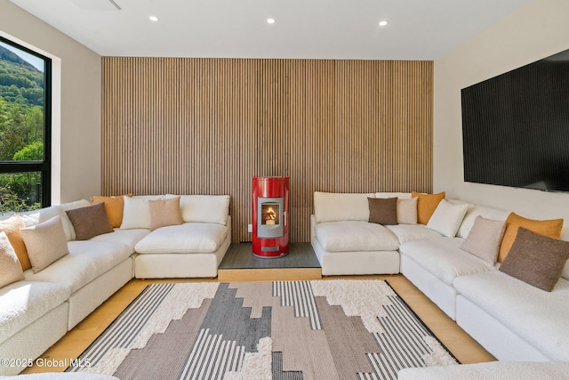 living area with recessed lighting, an accent wall, and wood finished floors