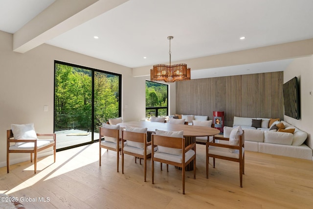 dining area with a chandelier, light wood-style floors, recessed lighting, and wooden walls