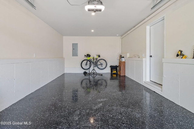 garage featuring electric panel, a wainscoted wall, and a garage door opener