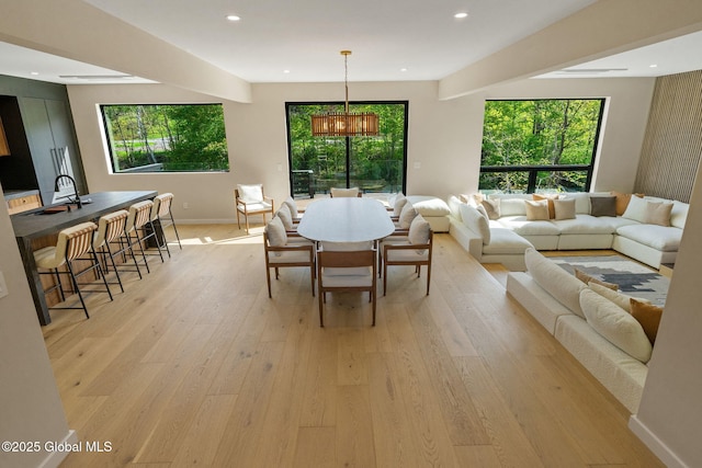 dining area with healthy amount of natural light, light wood-type flooring, baseboards, and recessed lighting