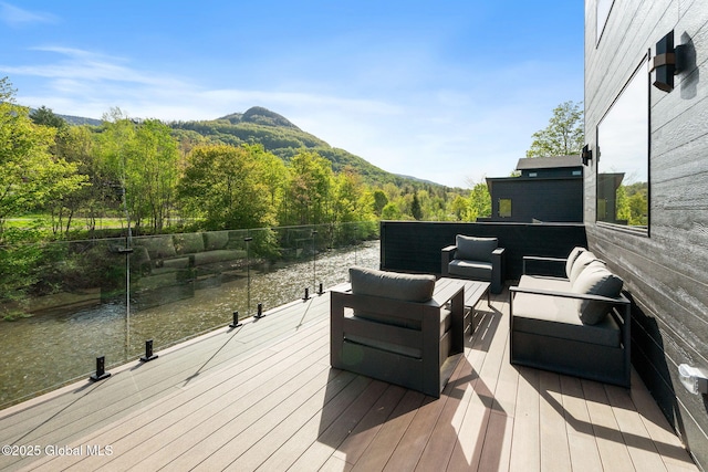wooden deck featuring outdoor lounge area, a view of trees, and a water and mountain view