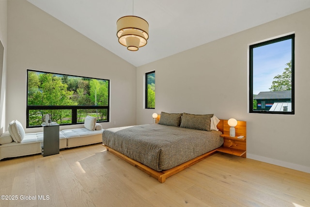 bedroom with wood finished floors, baseboards, and high vaulted ceiling