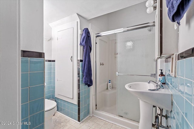 full bath with a shower stall, tile patterned flooring, a wainscoted wall, toilet, and tile walls