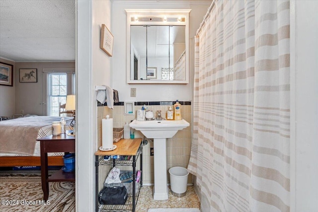 ensuite bathroom featuring ensuite bathroom, ornamental molding, curtained shower, tile walls, and tile patterned floors
