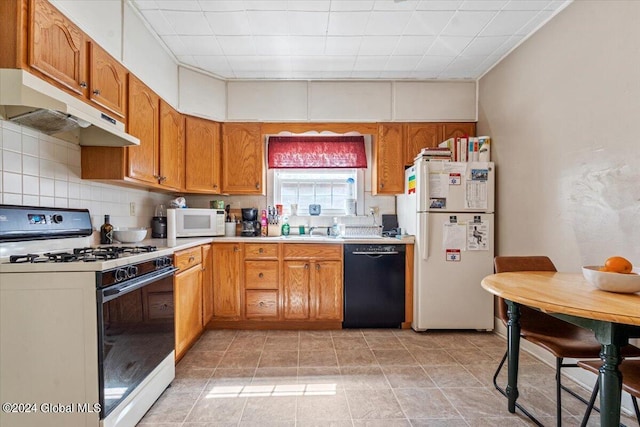 kitchen with white appliances, light countertops, under cabinet range hood, brown cabinets, and a sink