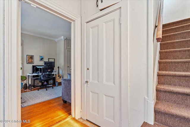 stairs with ornamental molding and wood finished floors
