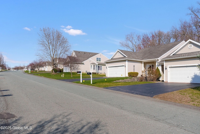 view of front of house featuring a garage, a residential view, driveway, and a front lawn