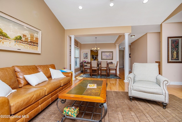 living room featuring baseboards, wood finished floors, an inviting chandelier, and ornate columns