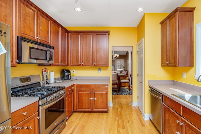 kitchen with stainless steel appliances, light wood-style flooring, a sink, recessed lighting, and light countertops