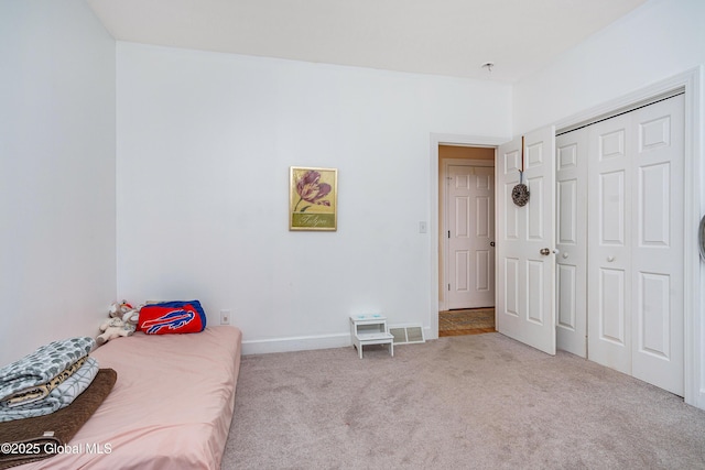 bedroom with a closet, visible vents, carpet flooring, and baseboards