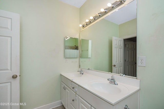 bathroom with double vanity, baseboards, and a sink