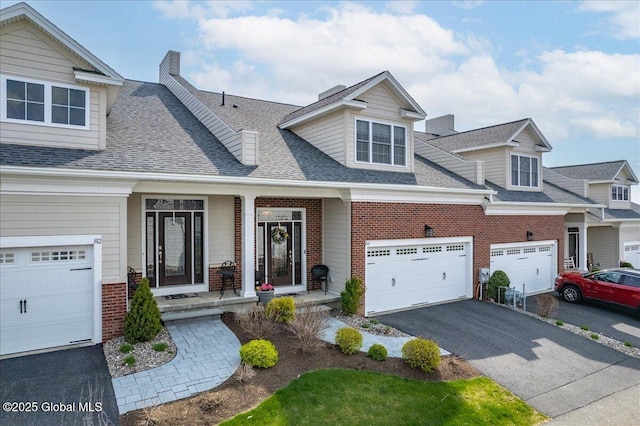 view of front of property featuring a shingled roof, driveway, and brick siding