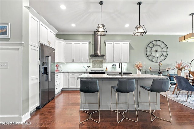 kitchen featuring white cabinets, a sink, wall chimney exhaust hood, high end refrigerator, and backsplash