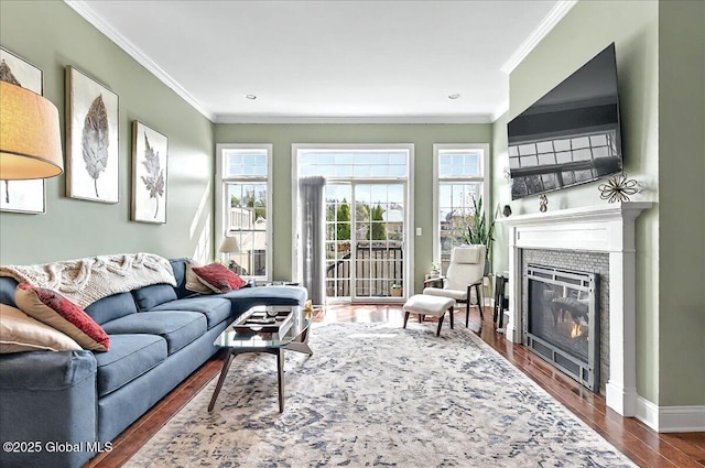 living room with crown molding, baseboards, a glass covered fireplace, and dark wood-type flooring