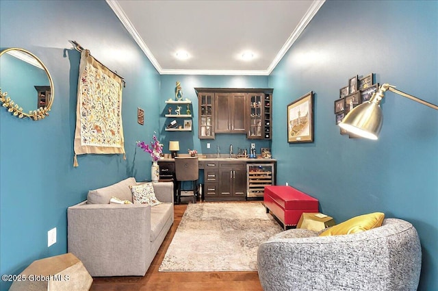 interior space featuring beverage cooler, ornamental molding, wood finished floors, and bar