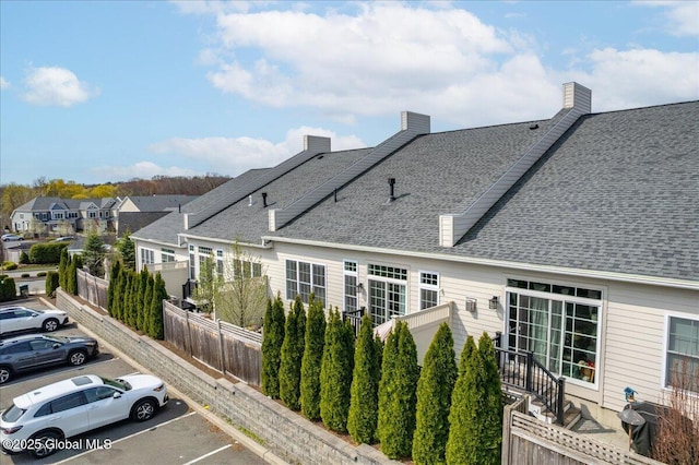 exterior space with a residential view, fence, uncovered parking, and a shingled roof
