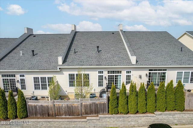 rear view of property with a shingled roof and fence private yard