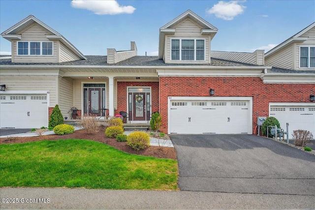 view of front of property featuring a porch, an attached garage, aphalt driveway, and brick siding