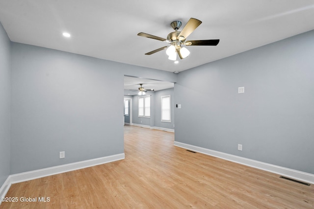 unfurnished room with light wood-style floors, baseboards, a ceiling fan, and visible vents